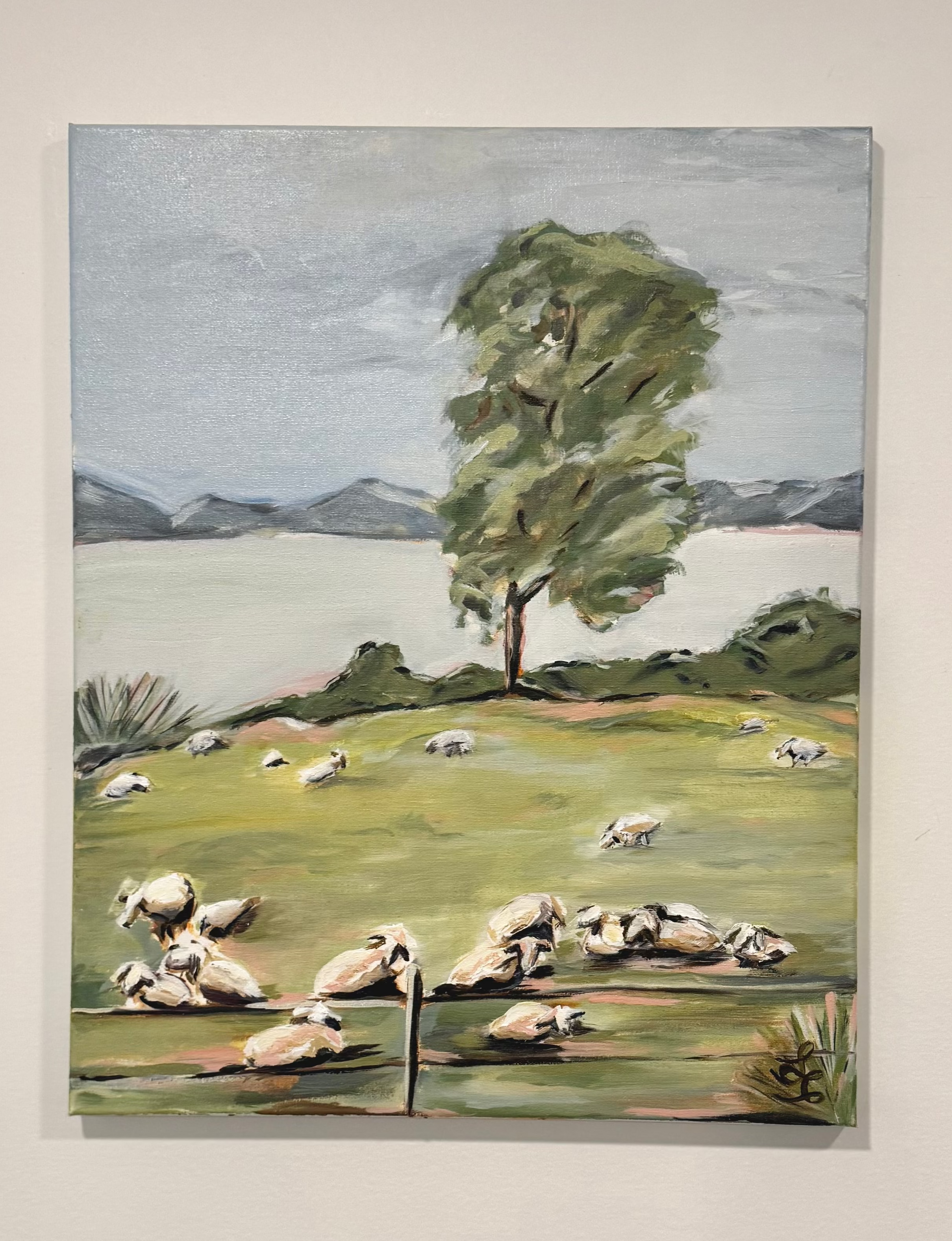 Biblical artwork. Painting of a pastoral scene with sheep, a tree, and mountains on a beige wall.