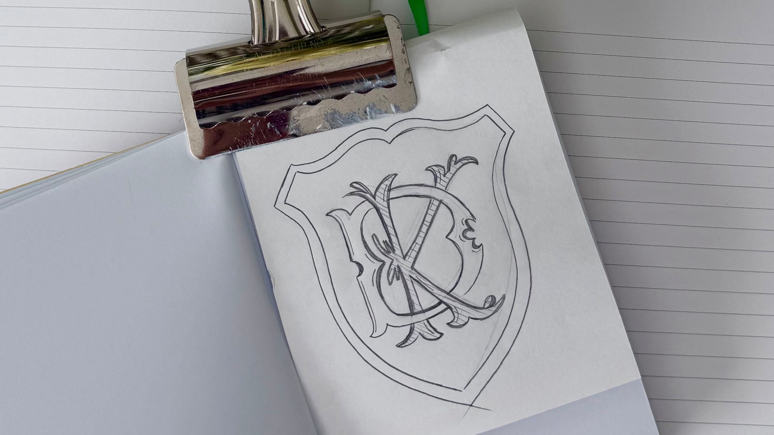 Sheets of paper with a crest design on a clipboard, surrounded by flowers.